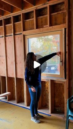 a woman standing in front of a window with her hand on the wall and pointing at it