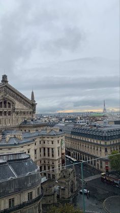 an aerial view of some buildings in the city with cloudy skies above them and one building has a clock on it's side