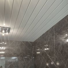 a bathroom with marble walls and lights on the ceiling