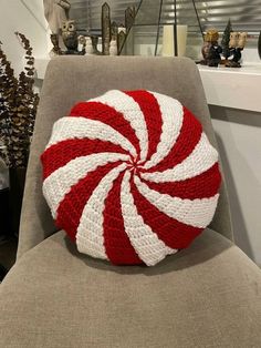 a red and white knitted candy cane pillow on a chair