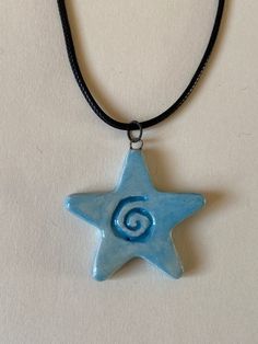 a blue ceramic star with a spiral design on it's side hanging from a black cord