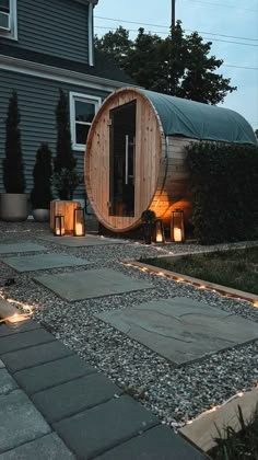 a wooden barrel sitting in the middle of a yard next to some lights and plants