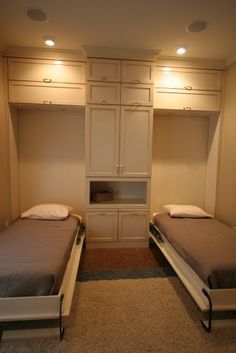 there are two beds in this room with built - in cabinets and drawers on the wall