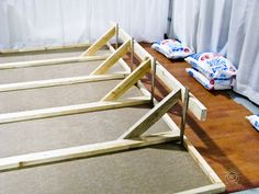 three pieces of wood sitting on top of a hard wood floor next to white curtains