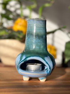 a blue vase sitting on top of a wooden table next to a potted plant