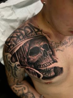 a man with tattoos on his chest has a skull and cross tattoo on his chest