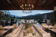 an outdoor dining area with tables, couches and chandelier hanging from the ceiling