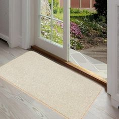 an open door with a rug on the floor in front of it and flowers outside