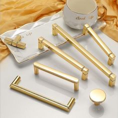 gold handles and knobs are sitting on a white surface next to a coffee cup