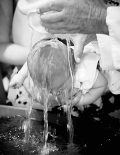 a baby is being washed in a sink with water from the faucet and hands