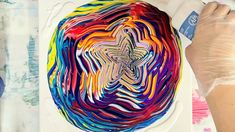 someone is painting on a plate with different colors