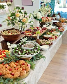 a table filled with lots of different types of food and flowers on top of it