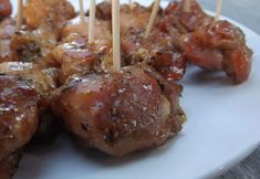 chicken skewers with toothpicks on top of them sitting on a white plate