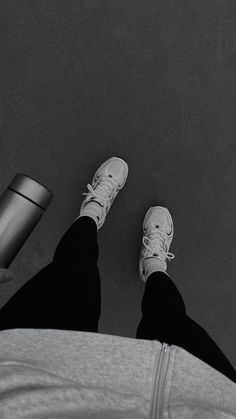 black and white photograph of person's feet with coffee cup in the foreground