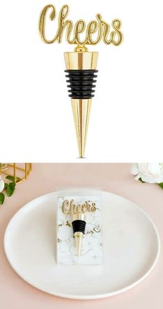 a white plate topped with a gold wine bottle stopper next to a black and white sign that says cheers