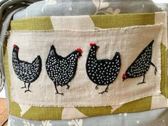 three chickens are on the side of a fabric covered bucket with handles and straps,