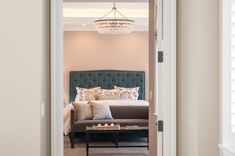 an open door leading to a bedroom with a bed and chandelier in it