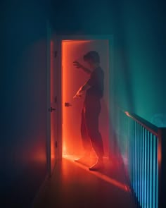 a person standing in an open doorway with red light coming from the door behind them