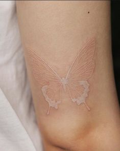 a white butterfly tattoo on the side of a woman's leg, it looks like she is flying in the air