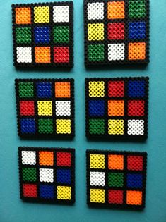 four different colored squares made out of perler beads on a blue surface with white and black dots