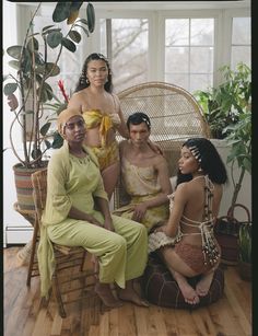 three women in bathing suits sitting on a wicker chair next to each other and one woman wearing a yellow dress