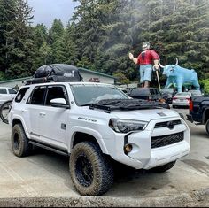 a man standing on the back of a white truck next to a blue bull statue