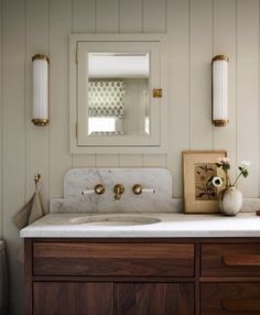 a bathroom vanity with marble counter top and wooden cabinetry, along with two wall sconces