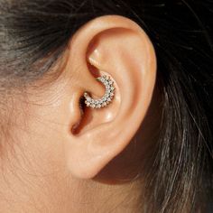 a woman's ear is shown with a diamond ring in the shape of a crescent