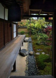 a wooden bench sitting in the middle of a garden next to a stone path and trees