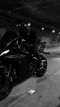 a man riding on the back of a motorcycle in a parking garage with his helmet on