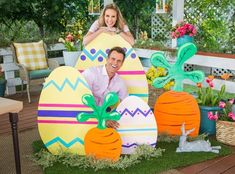 a man and woman sitting on top of giant easter eggs