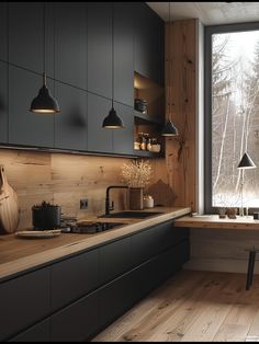 a kitchen with black cabinets and wooden counter tops next to a large window that looks out onto the woods