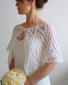 a woman in a white dress holding a bouquet of flowers and wearing a lacy shawl