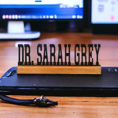 a wooden sign that says dr sagaha grey on top of a laptop