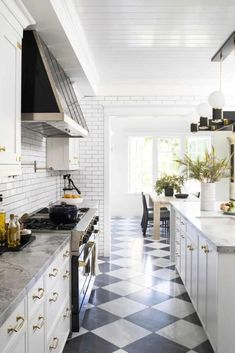 a black and white checkered floor in a kitchen with an oven, counter tops, cabinets, and sink