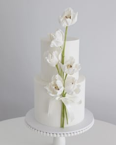 a three tiered cake with white flowers on top