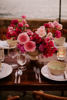 the table is set with pink flowers and silverware, along with plates and utensils