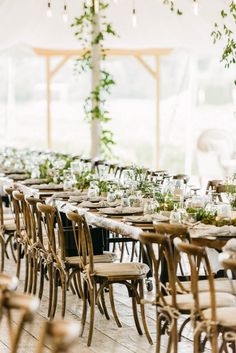 tables and chairs set up for an outdoor wedding reception with greenery hanging from the ceiling