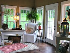 a living room filled with furniture and lots of windows next to a wooden floor covered in plants