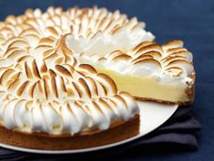 a white plate topped with a cake covered in frosting next to a slice of pie