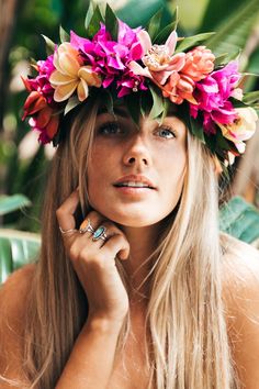 a woman wearing a flower crown with her hands on her face and looking off to the side