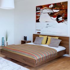 a bedroom with a large painting on the wall above the bed and nightstands next to it