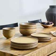 a wooden table topped with plates and bowls