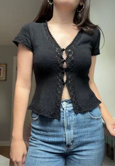 a woman in jeans and a black top is standing up with her hands on her hips