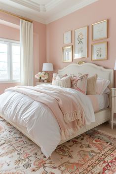 a bedroom with pink walls, white bedding and pictures on the wall above it