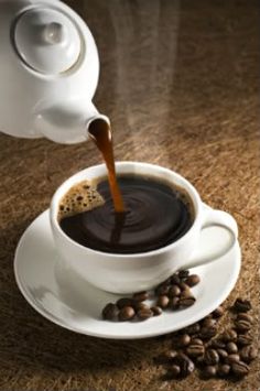 coffee being poured into a white cup on top of a saucer and surrounded by coffee beans