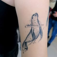 a tattoo on the arm of a woman with a seal in it's mouth