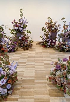 an arrangement of flowers arranged on the floor in front of two white chairs and one is empty