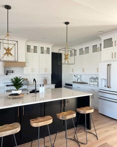 a kitchen with an island and stools in front of the counter top, surrounded by white cabinets