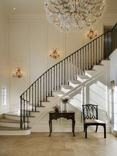 a chandelier hangs from the ceiling above a staircase